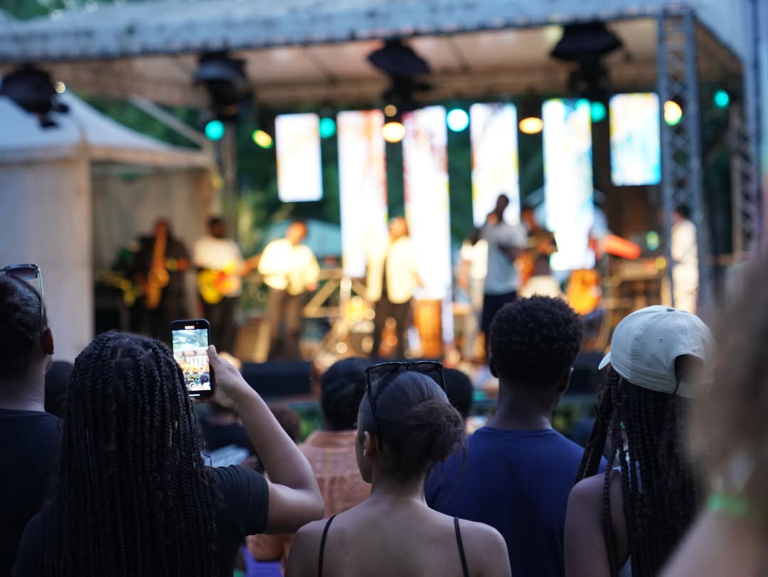 Foule joyeuse levant les mains lors d'un concert chrétien en plein air au coucher du soleil